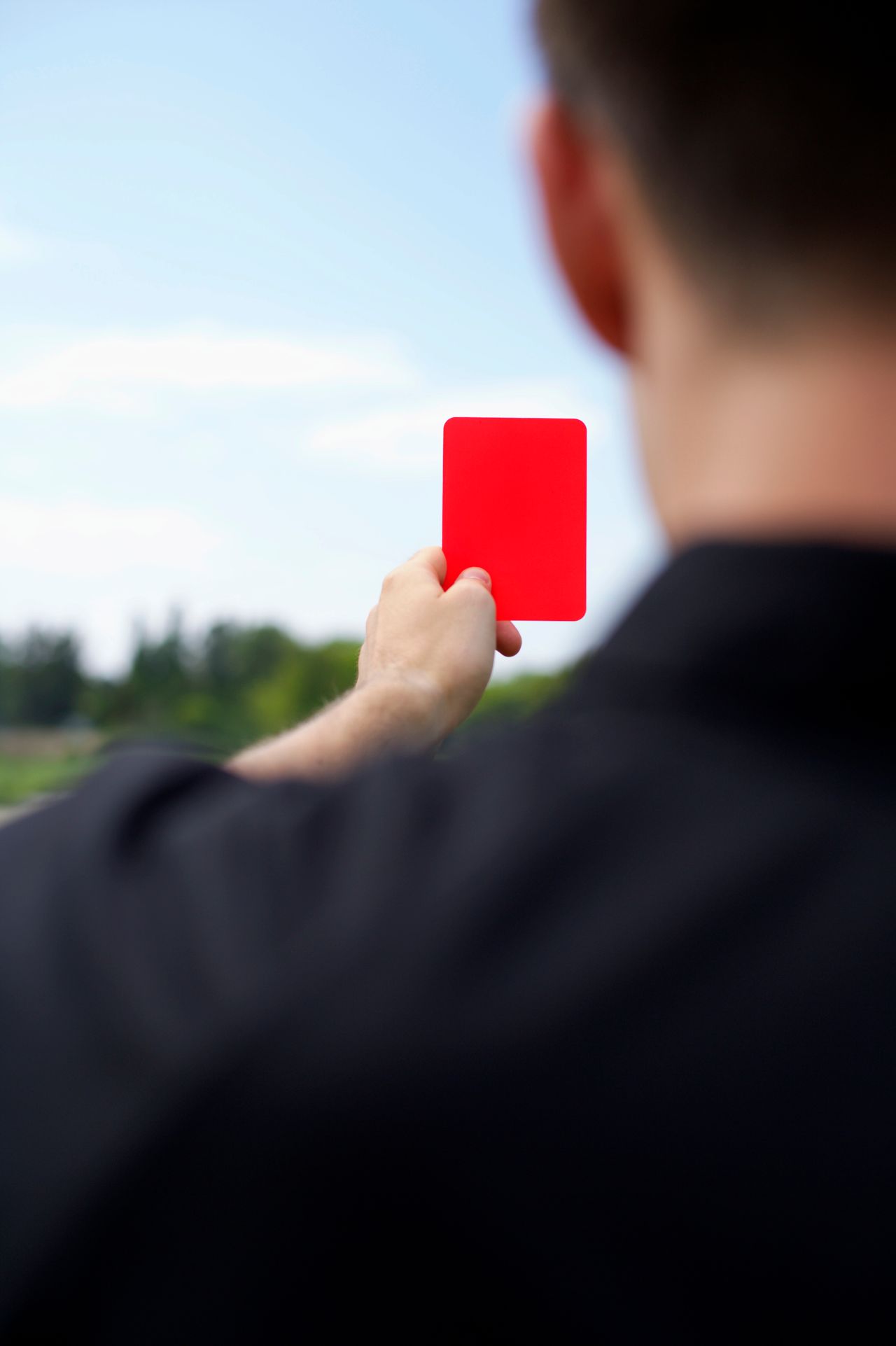 A red card held up on a soccer field, symbolizing sports fairness and controversy